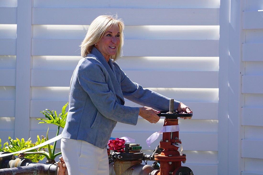 Spanish Main Yacht Club President Joan Sherry turns the valve to start the water.