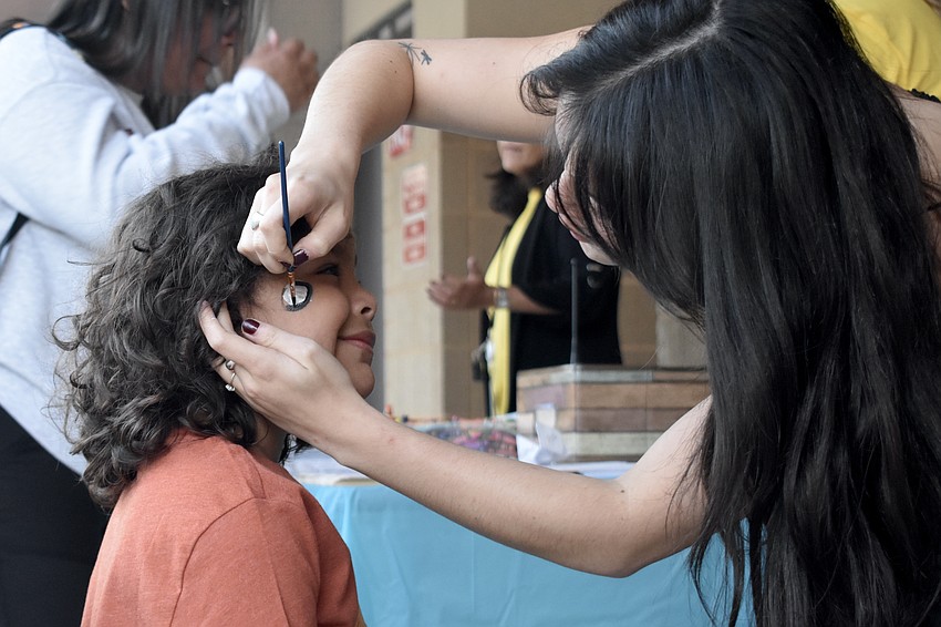Matteo Morales, 5, has his face painted by Sophia Cavalluzzi.