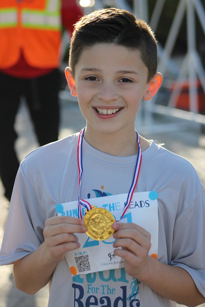 Sarasota's Abbie Forrest shows off his medal for winning the 9-13 age group race.