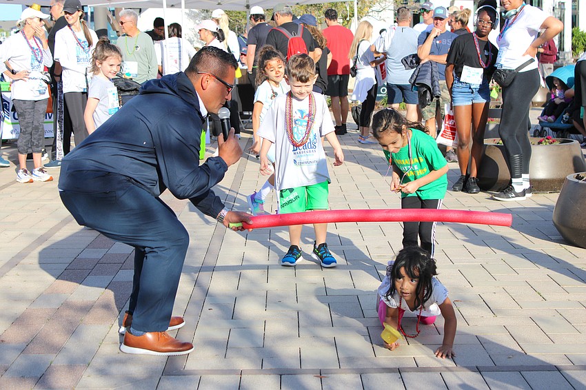 Lakewood Ranch 3-year-old Claire Garcia tries a different method during Limbo. DJ Jose Ramirez, holding the Limbo bar, donated his services for the second consecutive year.