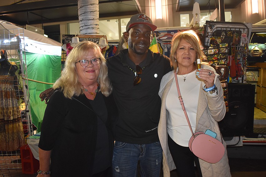 Wendy Smith, Kevin Dixon Dreadlock DaCity and Julie Papagi stand in front of Dixon's table, where Papagi just purchased a container of an essential oil.