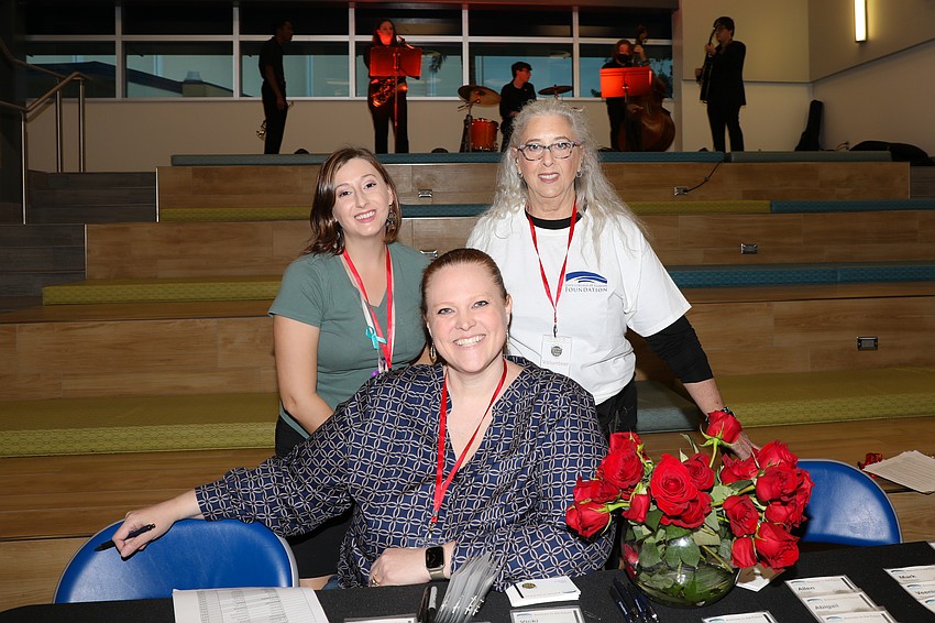 Madeline Mangas, Suzanne Anderson and Roxanne Petrilla check in guests while the band plays