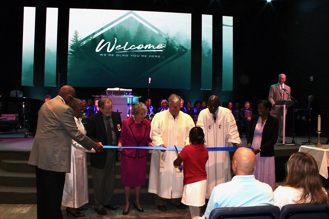Jim Gary, Rev. Teresa Waters, Larry Torino, Beverly Patrick, Rev. Durwood Foshee, Pastor Kevin James and Linda James hold on to the ribbon at the congregational grand opening celebration as Isabella Callaway makes the official cut. Courtesy photo
