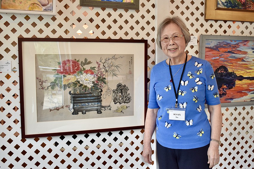 Susan Wu stands next to a Chinese brush painting she created for the Year of the Dragon. Each object holds a special meaning.
