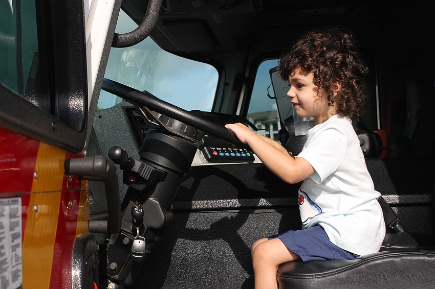 Waterside 2-year-old Sawyer Favara gets behind the wheel of a Sarasota County Fire Department truck at Eggstravaganza.