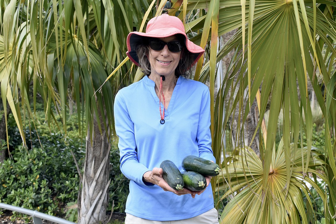 Joyce Norris holds some zucchini she has collected.