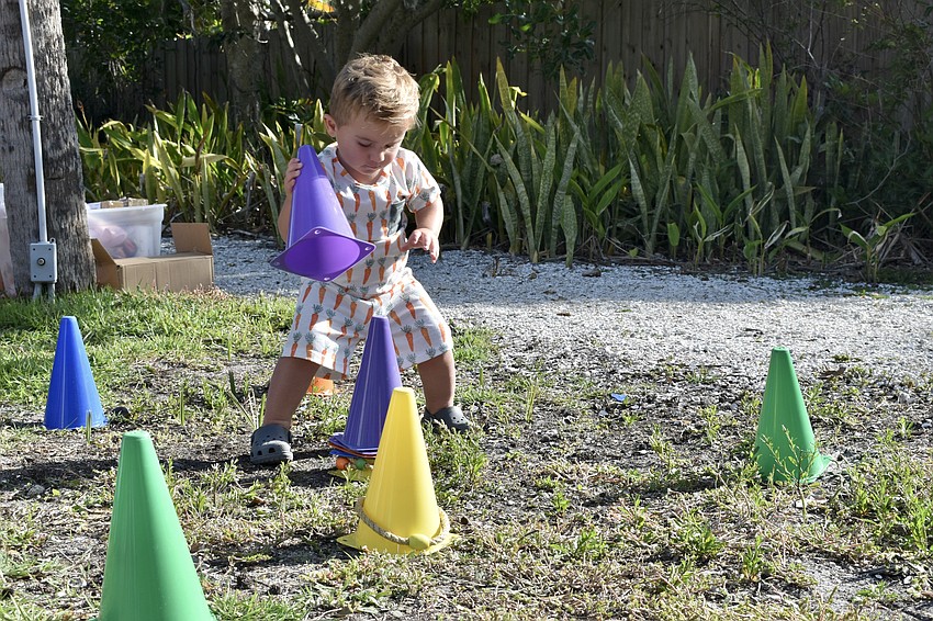 Mac Rogowski, 1, enjoys stacking the cones used in a ring toss game.