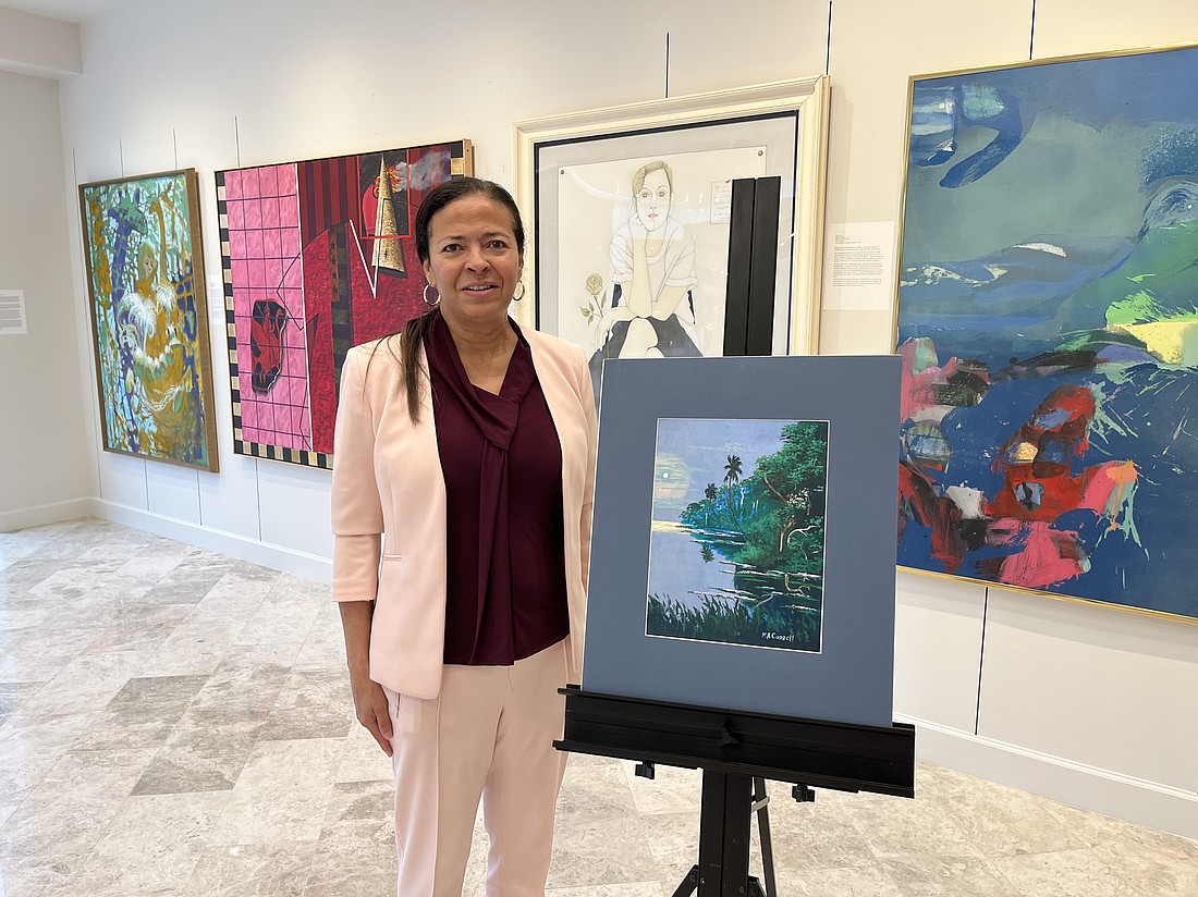Wanda Renee Mills poses in front of a painting by her mother, Mary Ann Carroll, known as the First Lady of the Florida Highwaymen painters.