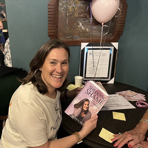 Krista Oakes holds a copy of her book, "Shedding Shame," during her launch party at Copperline Coffee and Cafe in Daytona on Tuesday, March 26. Courtesy photo