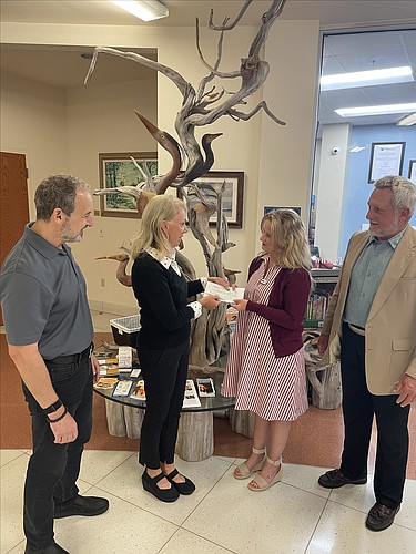 Flagler County Cultural Council Co-Chair Nancy Crouch hands a check to Flagler County Education Foundation Executive Director Teresa Rizzo as FC3's Jay Scherr and Lawson Glasergreen watch. Courtesy photo