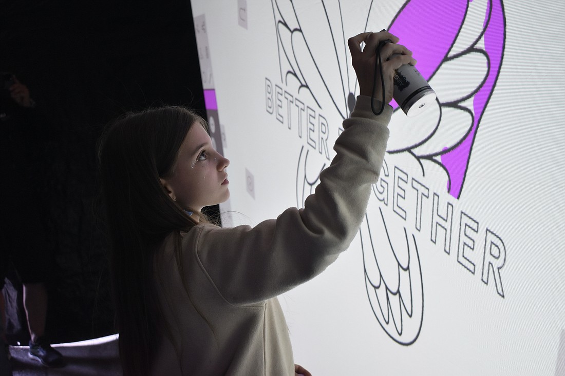 Snowden Mowry, 11, paints a "Better Together" mural on the digital graffiti wall.