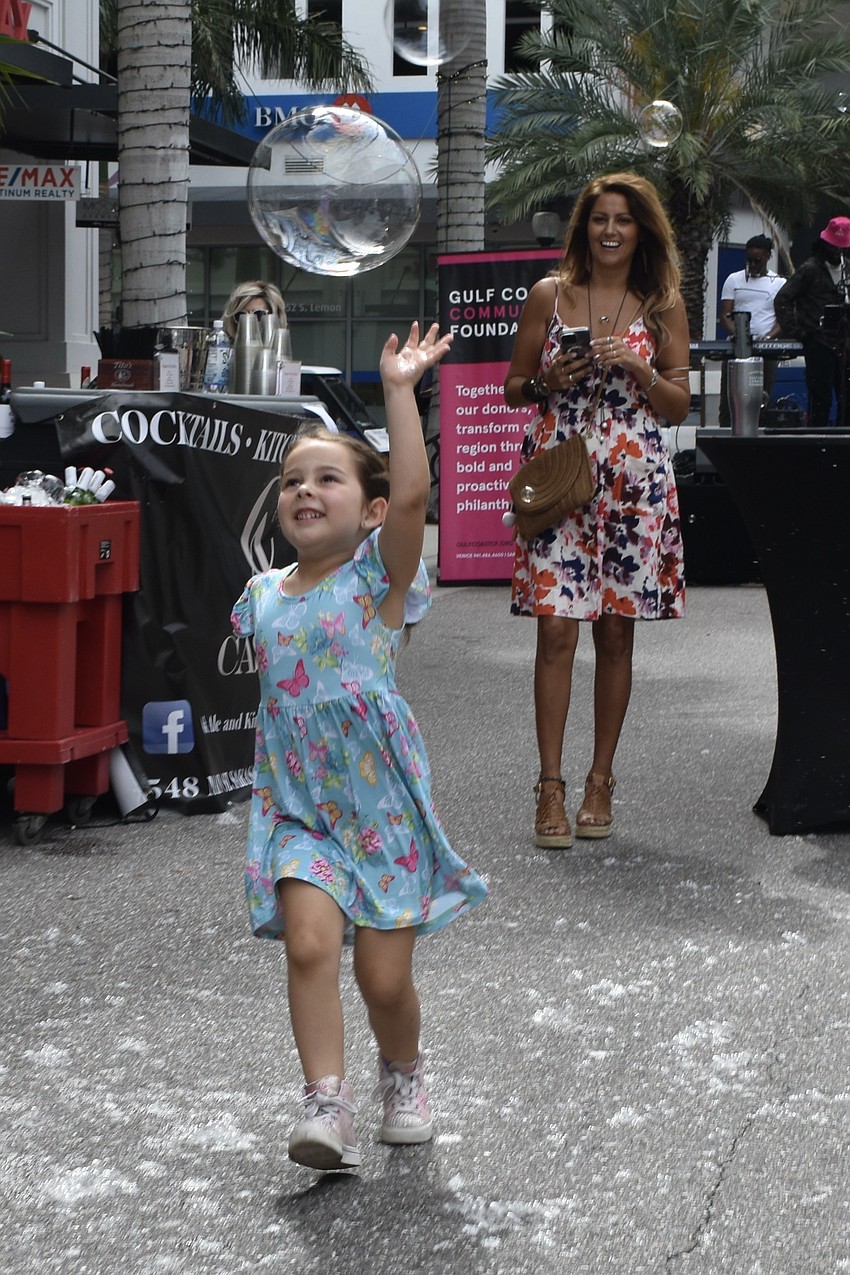 Piper Borgia-Howard, 5, chases a bubble, as Emilie Campos looks on.