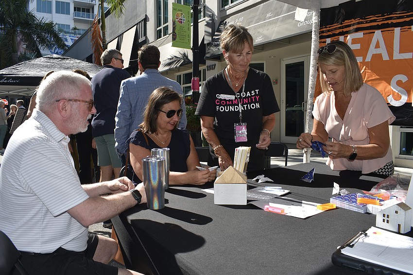 Ken Parrish, Jennifer Wilson, Harriet Thompson and Gigi Sanchez peform an oragami activity at the Health & Human Services table.