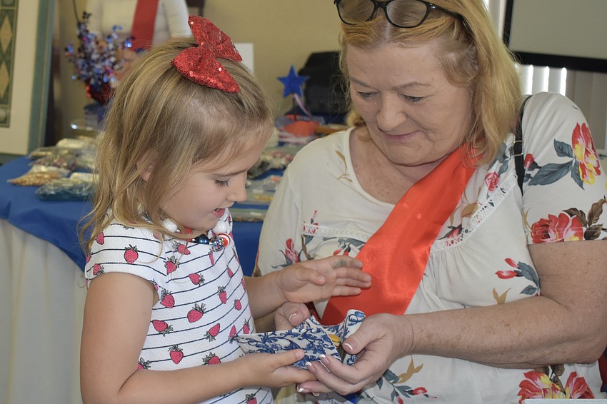 Chloe Westerberg, 6, delivers sweets from the tea table to her grandmother Deborah Thomas, who is staffing a DAR table.