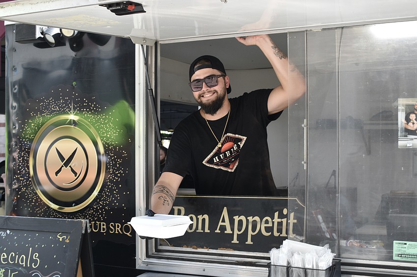 Jarek Dymek of Clean Plate Club SRQ holds out a meal for a guest.