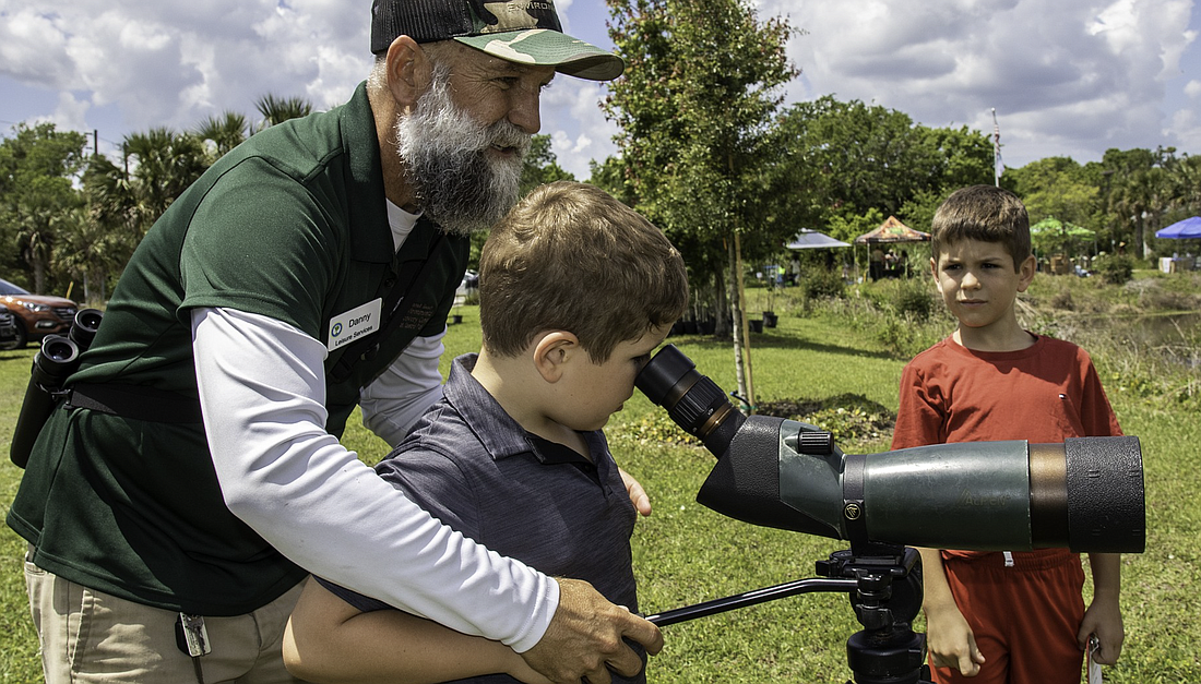 Danny Young, a leisure services volunteer, and brothers Caleb, 6, and Isaac Santos, 7, spot a rare bird at the 2023 Ormond Beach Earth Day event. File photo