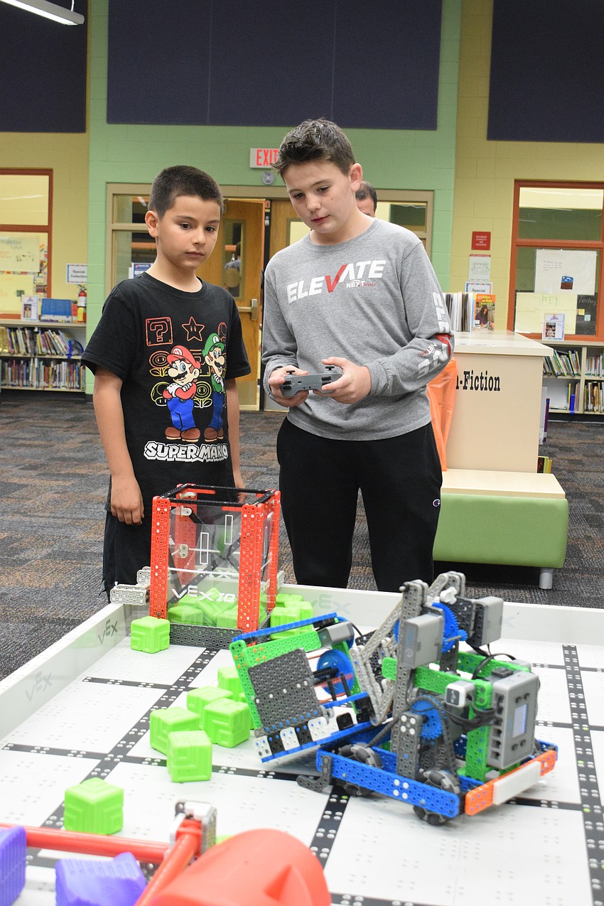 Third grader Jeremy Hoyos listens carefully as R. Dan Nolan Middle Schooler sixth grader explains how to use the controller to move the robot he created.