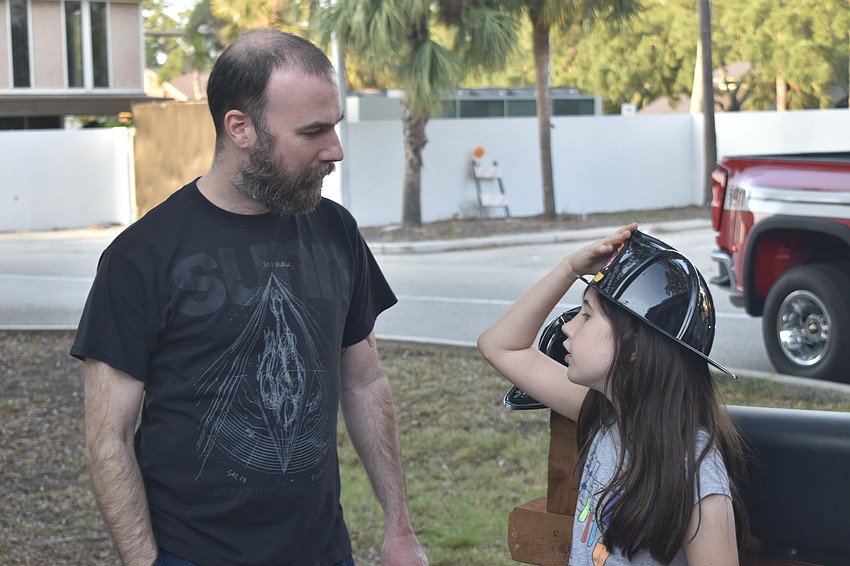 Stephen Geisler talks to his daughter Harper Geisler as she tries on a fire hat from the Sarasota County Fire Department.