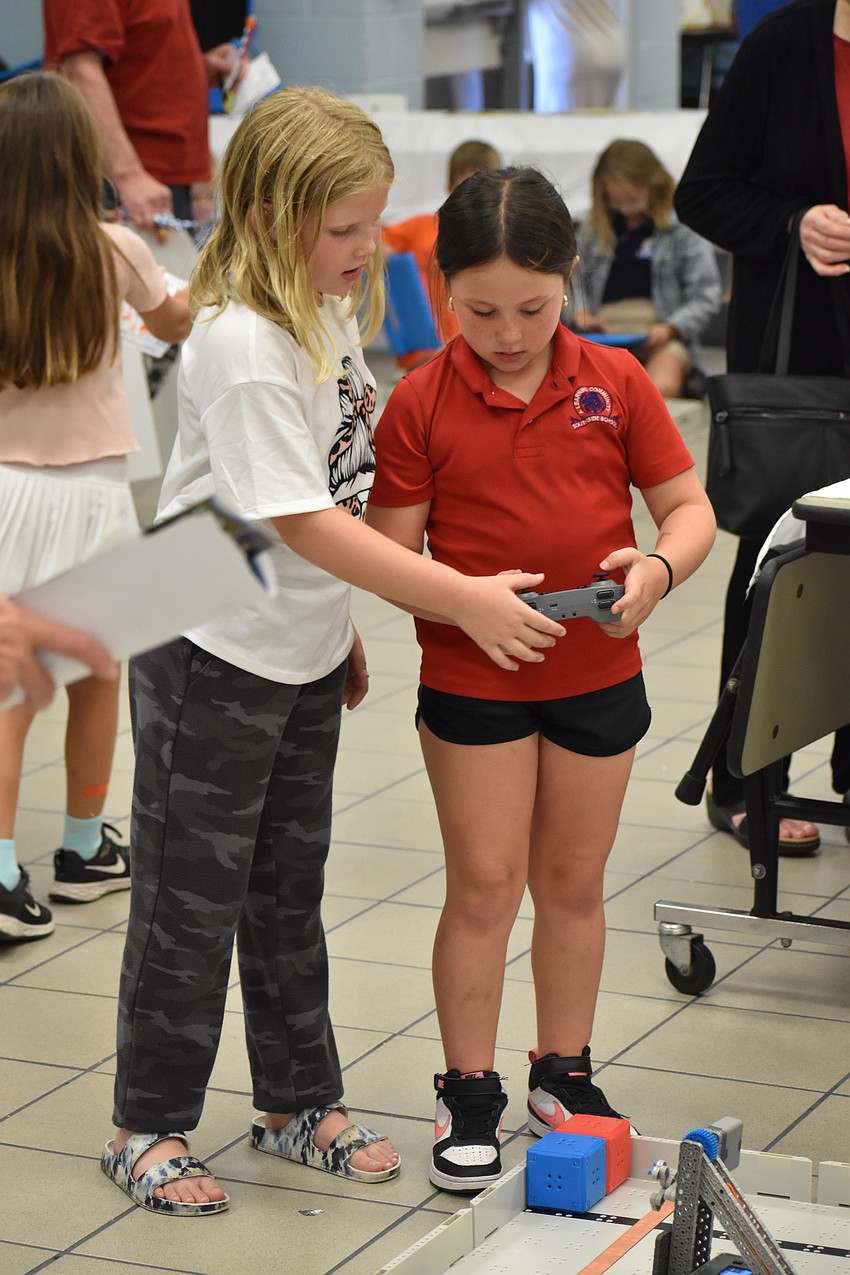 Second graders Lila Cigich and Valerie Wright control a VEX robot.