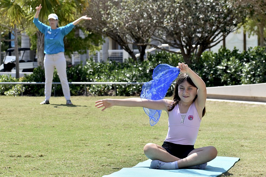 Frances Bermudez, activation and program manager at The Bay Park, performs yoga moves behind Elif Pektas, 8.