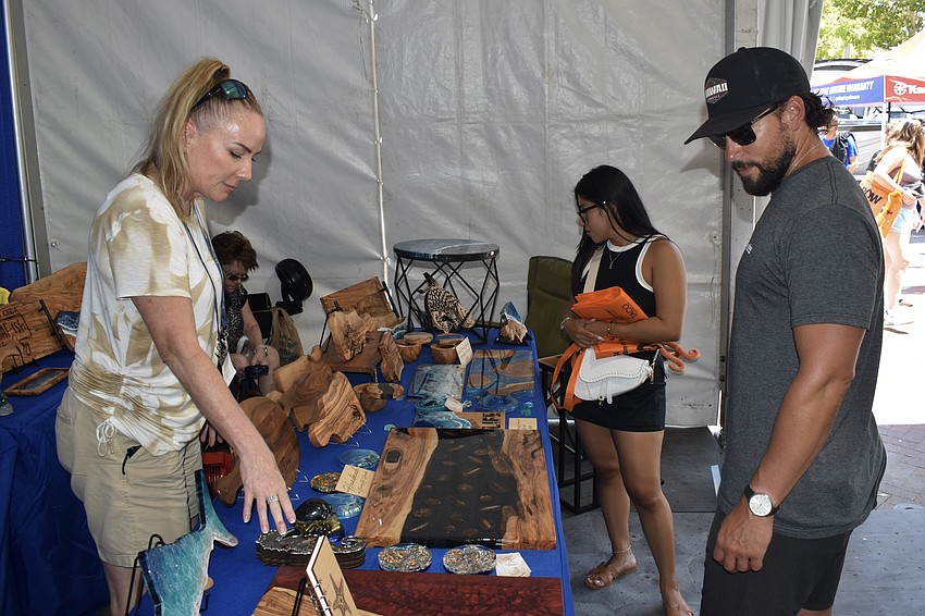 Artist Tricia Bolds showcases resin cutting boards to Amanda Batt and Anthony Flinn.