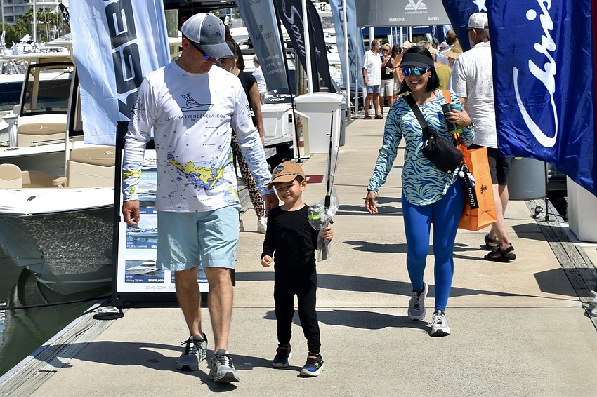Leonardo Gonzalez, Noah Ortega, 3 and Geraldine Marquez walk through the boat show, with Noah carrying his pole from the fishing clinic.