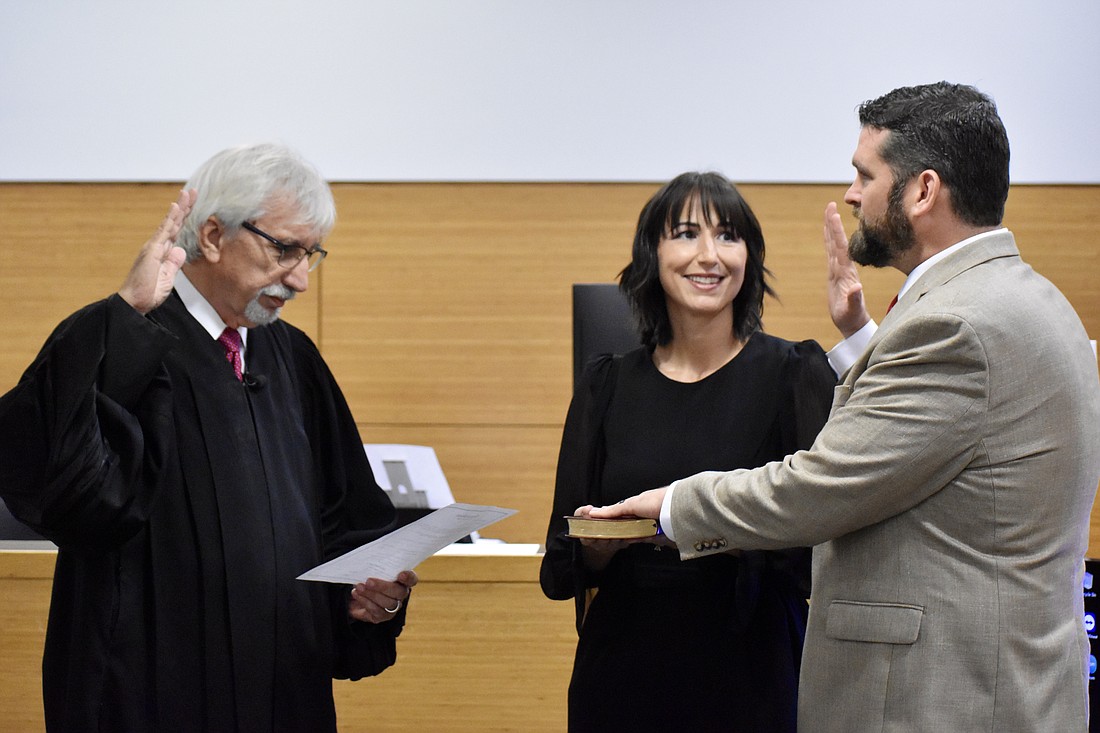 Judge Gilbert A. Smith Jr. swears in James Satcher as the new Supervisor of Elections. Satcher is joined by his wife Monica.