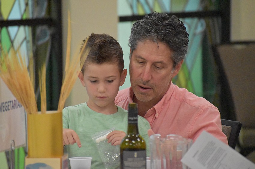 Hudson Bloom, 6, places drops of grape juice on his plate to represent the 10 plagues, with Justin Bloom.