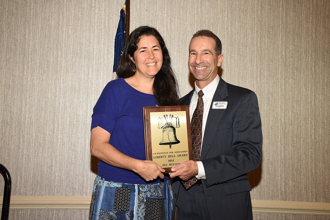 Jill Mullins, an art teacher at West Riverside Elementary School, accepts the  2024 Liberty Bell Award from JBA President Blane McCarthy.