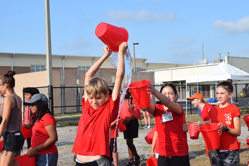 Fifth grader Norton Lincoln dumps water into Alexandra Marcus' bucket, but most of the water hit the ground instead.