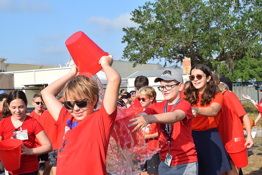 Fifth grader Alex Kulyk tries his best to get as much water in fifth grader Benjamin Rodriguez's bucket while fifth grader Alina Matevosova waits her turn.