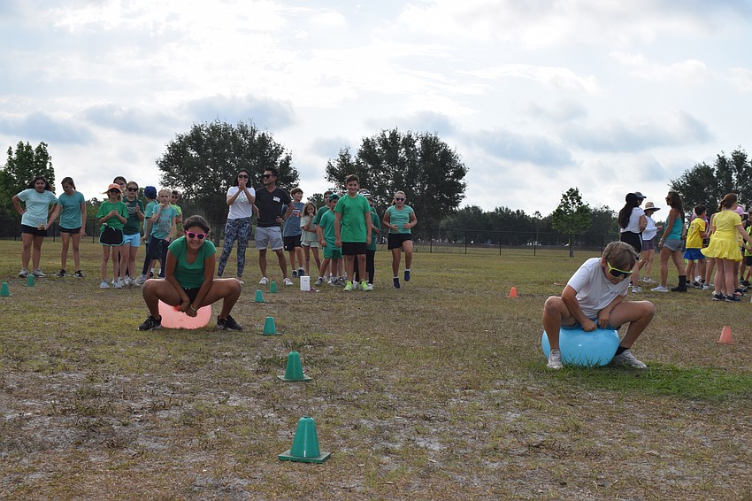 Students race against each other in a bouncy ball race. It's harder than it looks as students fell trying to keep their balance on the ball.