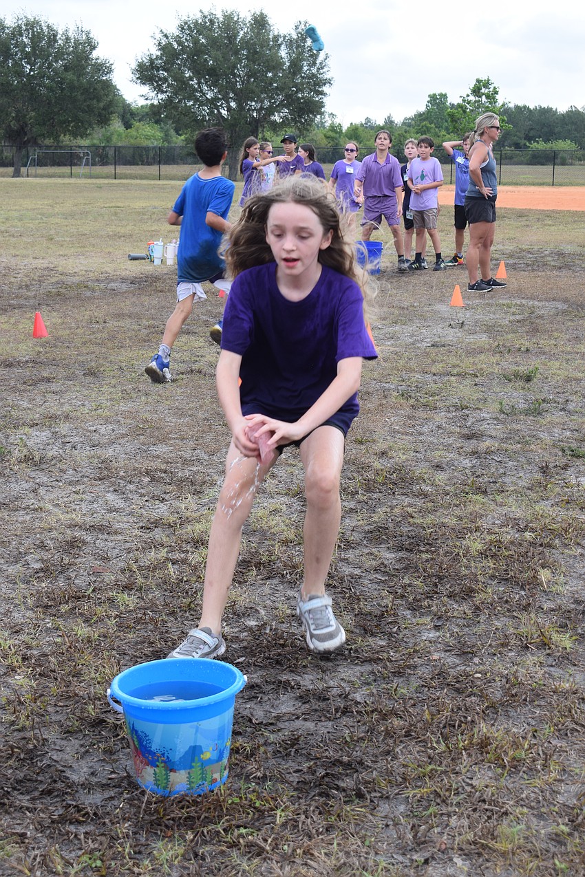 Fifth grader Kayla Walsh runs as fast as she can to squeeze water from her sponge into the bucket. Her team placed second.