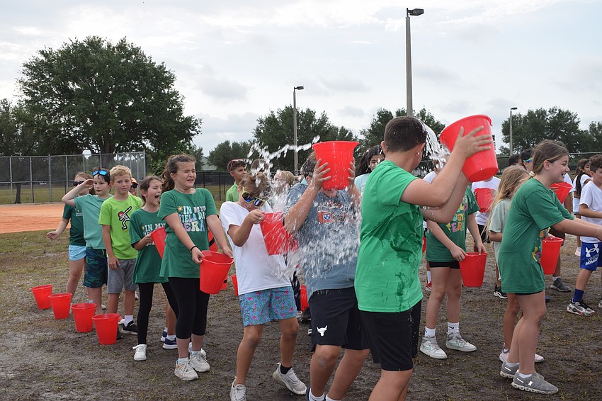 Fourth graders line up to try to get as much water from bucket to bucket. Most of the water ended up on the students.