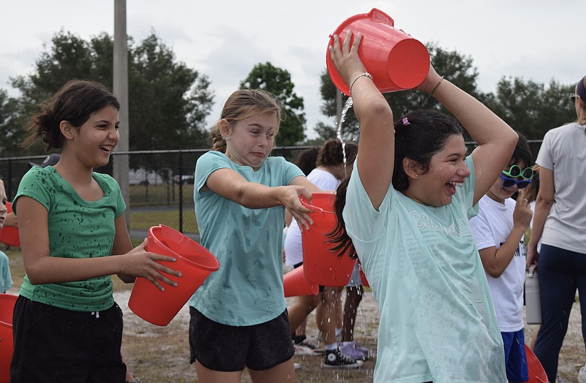 Fourth graders Lara Tavares and Ava Gilbank try to capture as much water from Mhiia Serrato without getting wet.