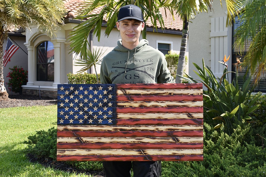 Lorenzo Liberti holds one of his hand carved flags.