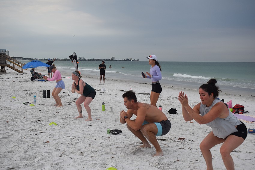 Sami Hobbs, Jamie McDermott-Galles, Kathryn Adelman, Westley Adelman and Shannon Hill do squats while their mothers do lunges across the sand.