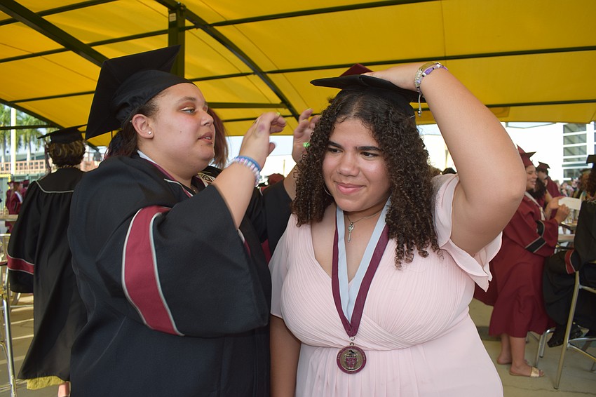 Braden River High's Airanna Gibbons helps Sivannah Gonzalez pin her graduation cap on her head.