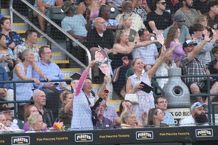 A family waves around cutouts of their Braden River High graduate's head.