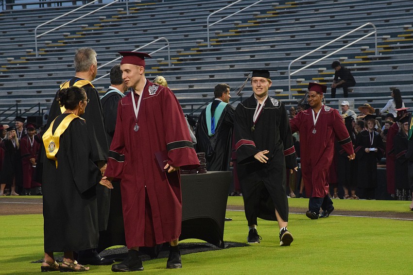 Braden River High graduates Christopher Hemp, Thomas Hemp and Andrick Hernandez make their way across the field at LECOM Park to receive their diplomas.