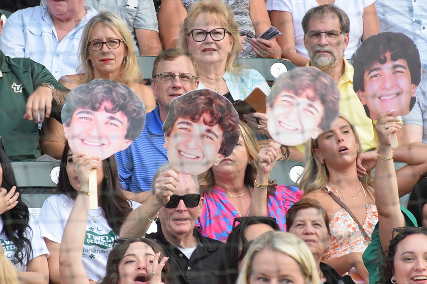 A family holds up cutouts of a Lakewood Ranch High School's graduate's head and cheers for him.