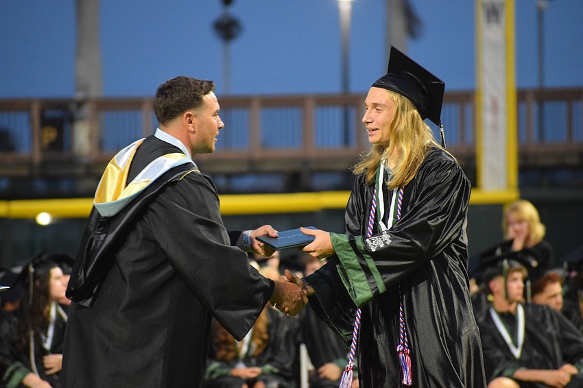 Thomas Bellantonio, an assistant principal at Lakewood Ranch High School, hands Gabriel Legutko his diploma.