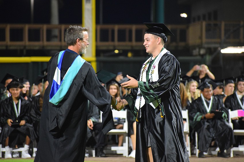Mike Staker, a Lakewood Ranch High School assistant principal, hands the final graduate of the night, Jack Zolecki, his diploma.