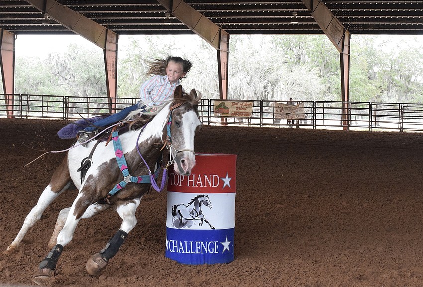 Harper Davis, who is 5 years old, races through the arena, circling barrel after barrel.