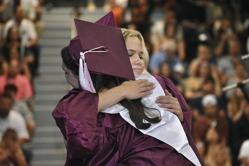 Senior class vice president Molly McWilliams hugs president Grace Flint as they trade places at the podium.