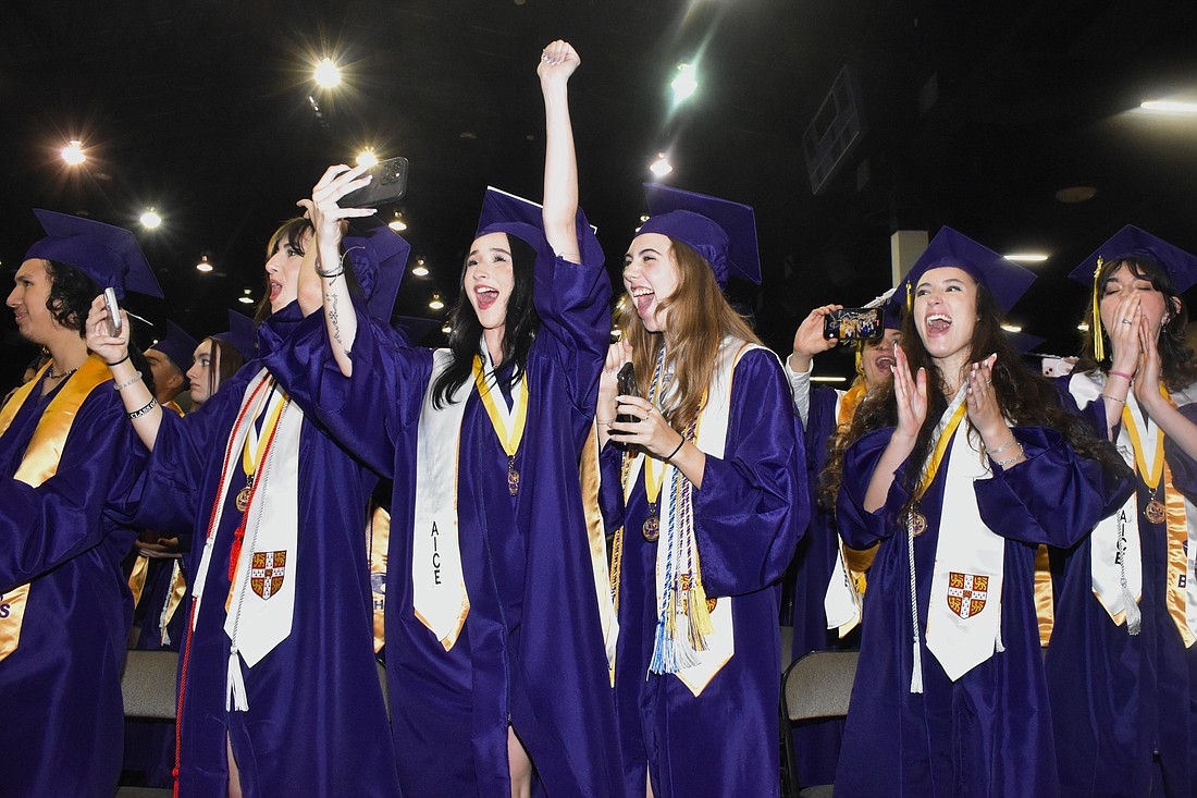 Students, including Emma Green and Cora Gerdes (center), celebrate during the moment of graduation.