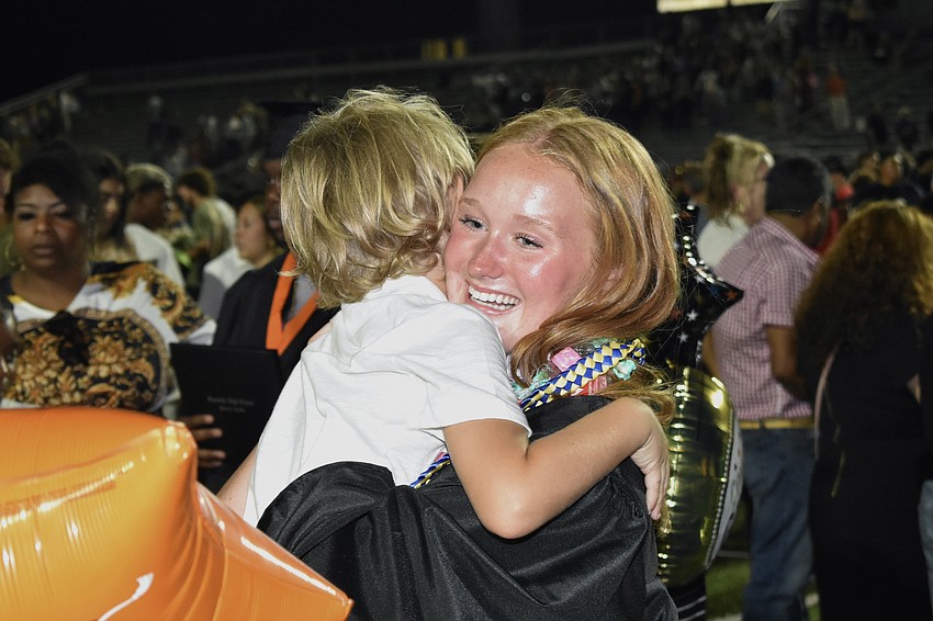 Julien Carlsson, 7, gives his sister Isabelle Carlsson a hug after graduation.