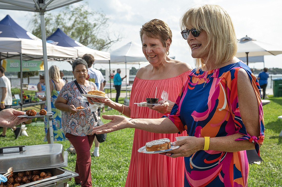 Phyllis Stauffenberg (center) and Jeanne Emmett (right) stop by the Grind Gastropub tent to get some meatballs from Taylor Lahna at the 11th annual Taste of Ormond as Dolores Hartshorn  (left) makes her way there to do the same. Photo by Michele Meyers