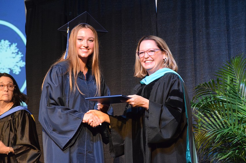Charlie Hugill accepts her diploma from Deb Otey, the head of school.