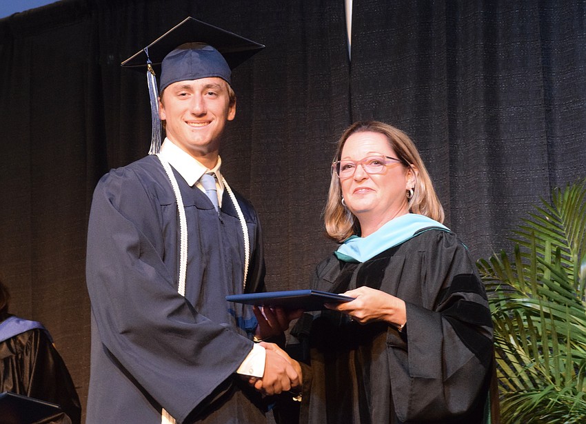 Nolan Naese accepts his diploma from Deb Otey, the head of school.
